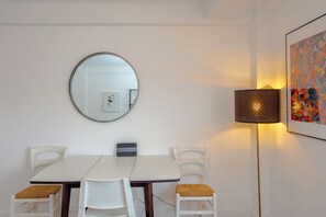 Un coin repas comprenant un miroir rond, une table et deux chaises.