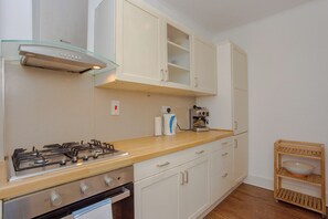A kitchen with a gas stove, oven, and a coffee machine. - Contemporary 2BD Flat in Bayswater, West London (London)