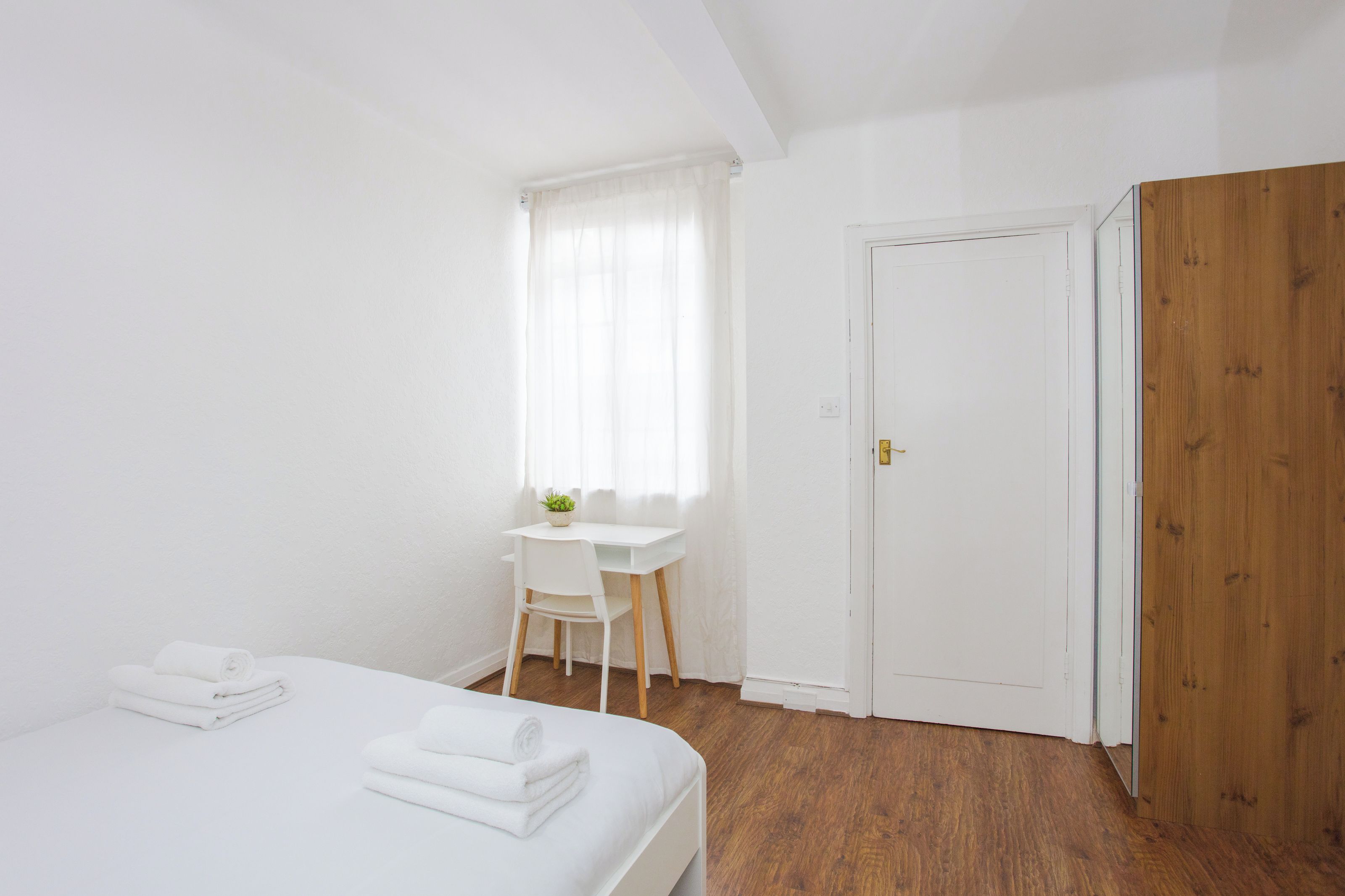 A bedroom with a bed, a desk, and a door.