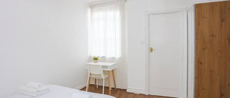 A bedroom with a bed, a desk, and a door.