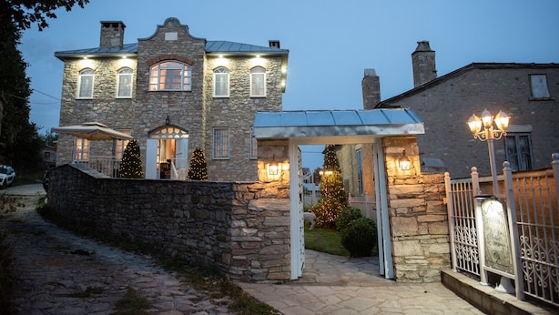 A stone building with a covered porch and Christmas lights.