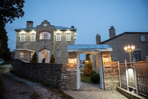 A stone building with a covered porch and Christmas lights. - Dandy Villas Nymfaio - Snow Fairy - Sauna (Nymfaio)