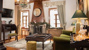 A cozy living room with a fireplace, wooden furniture, a chandelier, and a television.