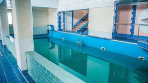 A swimming pool with blue tiles and a staircase leading to an upper level.