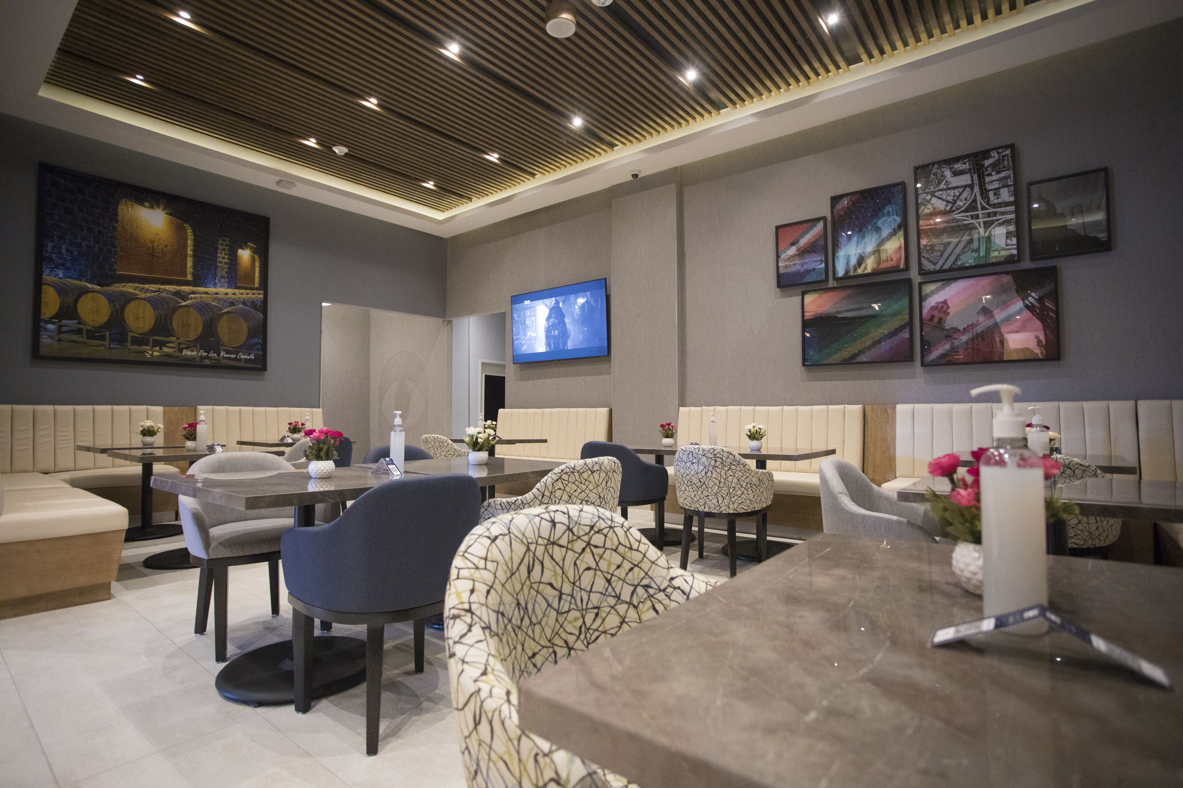 A modern dining area with booths and tables, a flat-screen TV, and artwork on the walls.