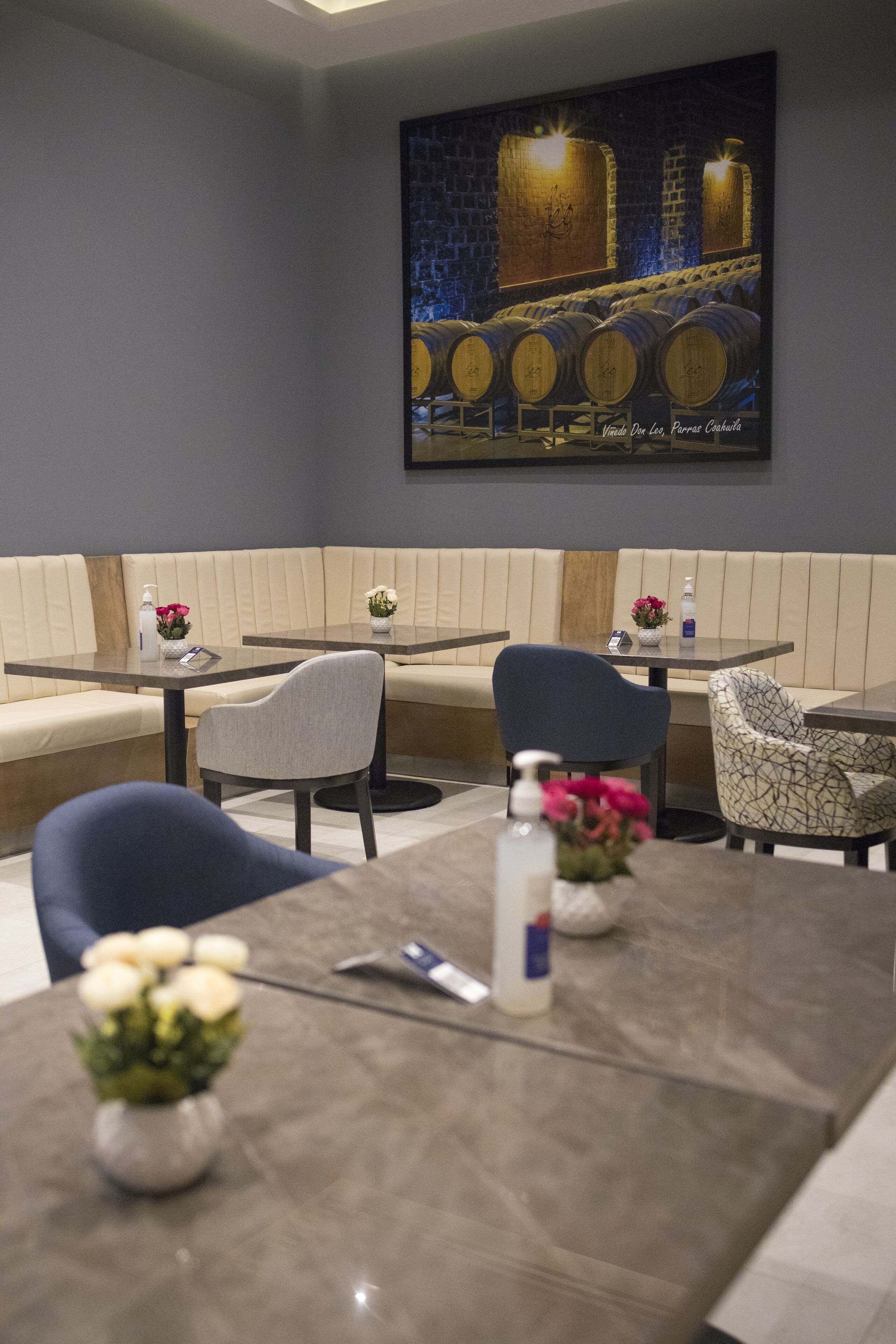 Un restaurant au décor moderne, avec un long banc servant de siège, des tables avec des chaises et un grand tableau accroché au mur.