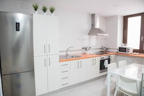 A modern kitchen with white cabinets, stainless steel appliances, and a window providing natural light.