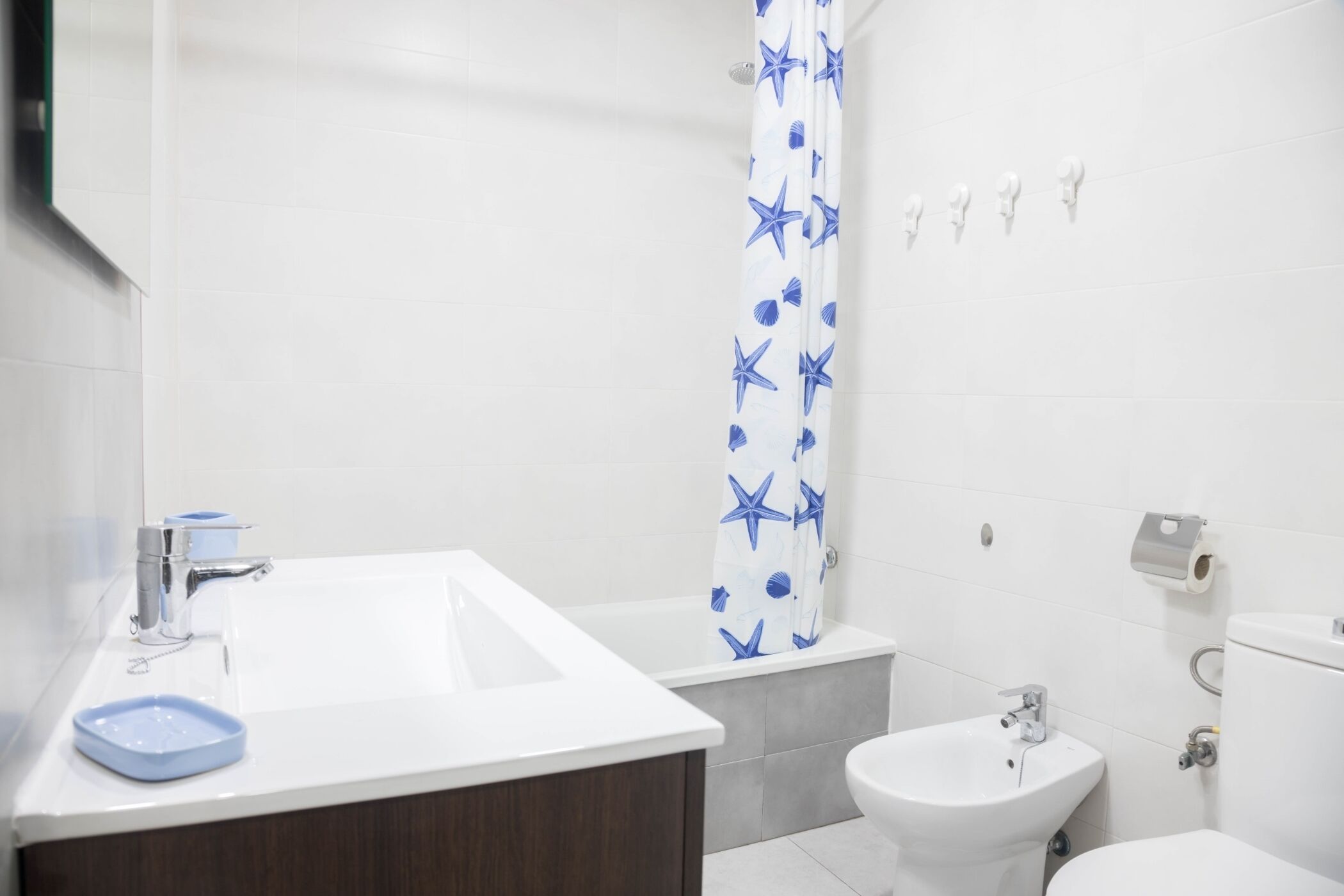 A bathroom with a white sink, a bidet, and a toilet.