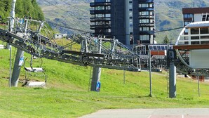 A modern high-rise building with a ski lift in the foreground and a mountain in the background. - Croisette / Dorons / 6 places (LES MENUIRES)