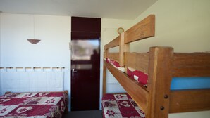 A small, compact room with two bunk beds, a door, and a hanging light fixture. - Croisette / Dorons / 6 places (LES MENUIRES)