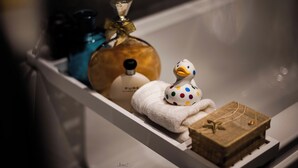 Een wastafelmeubel met een witte handdoek, een zeepdispenser in de vorm van een eend en een klein houten doosje.