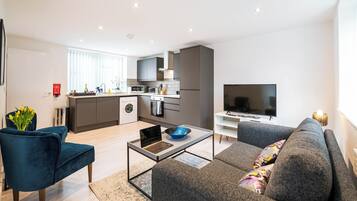 A modern apartment with a kitchen, living area, and a TV.