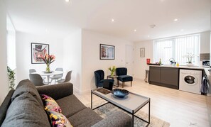 A modern living room with a sofa, a coffee table, and a dining area with chairs and a table.