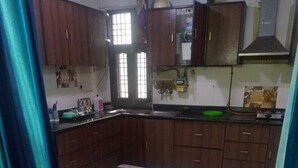 A kitchen with dark wooden cabinets, a white countertop, and a tiled floor. - ADB Rooms Knights Inn (New Delhi)
