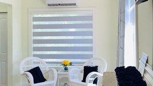 A room with a white wicker sofa set, a small table with a vase of yellow flowers, and a blue mat on the floor. - Miami Skyline Luxury Suite With Private Patio and Parking . (Miami)