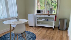 A compact kitchen with a microwave, coffee maker, and small refrigerator. There's a round table with chairs and a blue rug. - Miami Skyline Luxury Suite With Private Patio and Parking . (Miami)