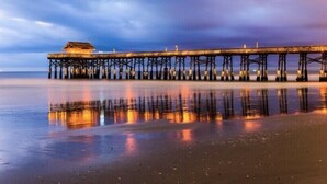 Un muelle se adentra en aguas tranquilas, con un edificio al final.