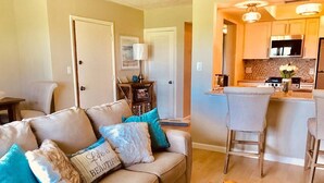 Una sala de estar con un sofá, una mesa de centro y una zona de cocina con una mesa de comedor y sillas.