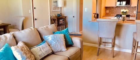 A living room with a sofa, a coffee table, and a kitchen area with a dining table and chairs.