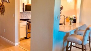 Una cocina moderna con una isla central, taburetes de bar y vista al área de comedor.