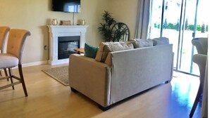 Una sala de estar con chimenea, un televisor de pantalla plana y un ventanal grande.