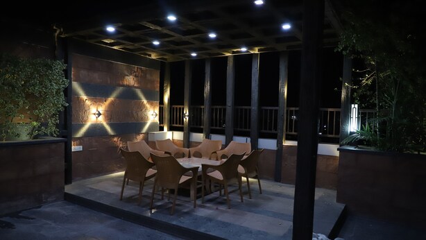 An outdoor patio with a round table and chairs, surrounded by walls with built-in lighting. - Republic Hotel (Patna)
