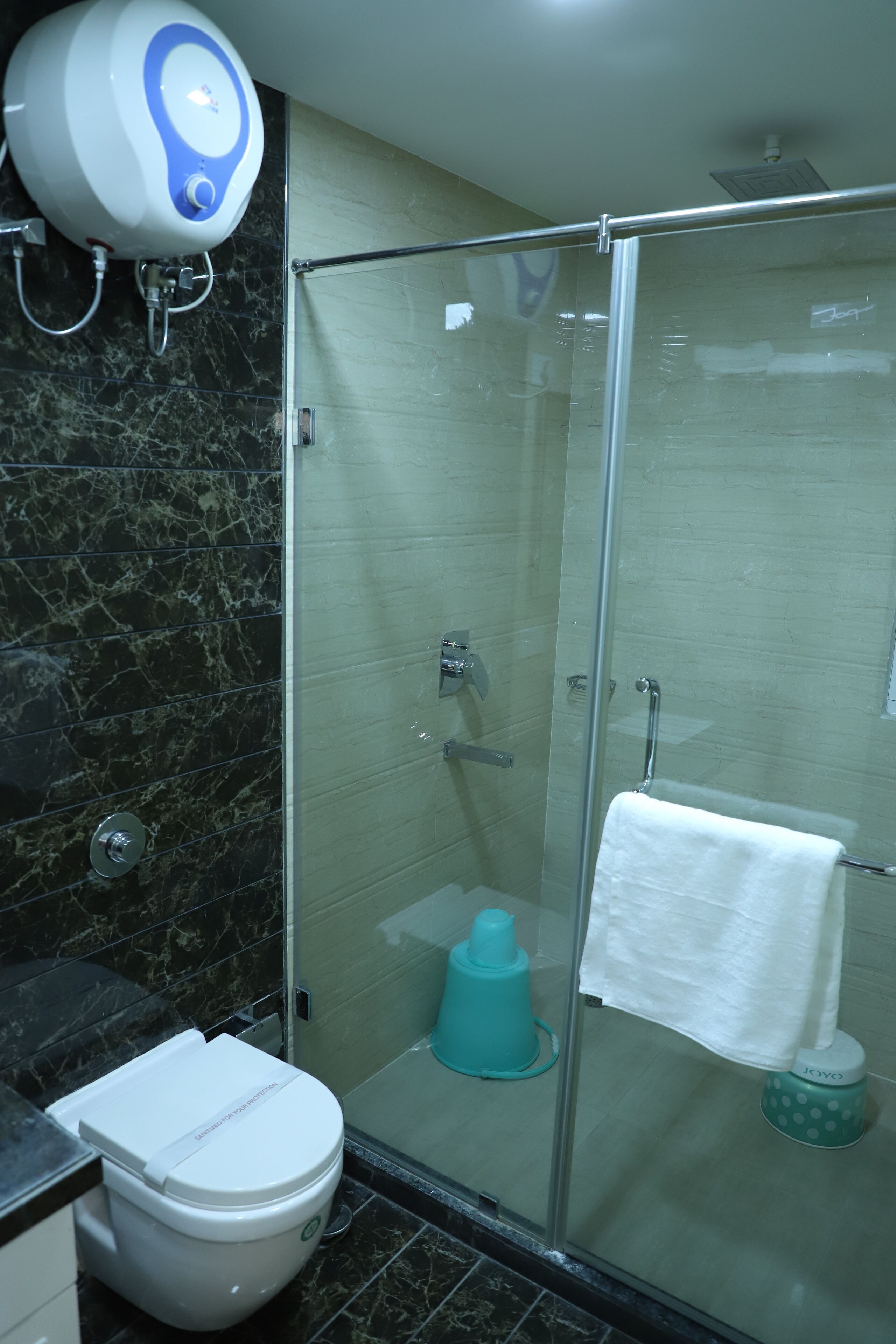Een moderne badkamer met een douchecabine van glas, een toilet en een handdroger.