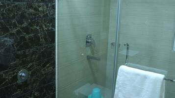 Een moderne badkamer met een douchecabine van glas, een toilet en een handdroger.