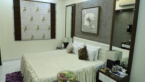 A bedroom with a bed, bedside tables, a mirror, and a wall-mounted artwork. - Republic Hotel (Patna)