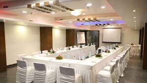 A conference room with a long table, chairs, and a projector screen. - Republic Hotel (Patna)