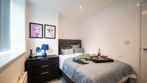 A bedroom with a bed, a nightstand, a dresser, and two framed pictures on the wall. - Windmill House Apartment 4 (Lytham Saint Annes)