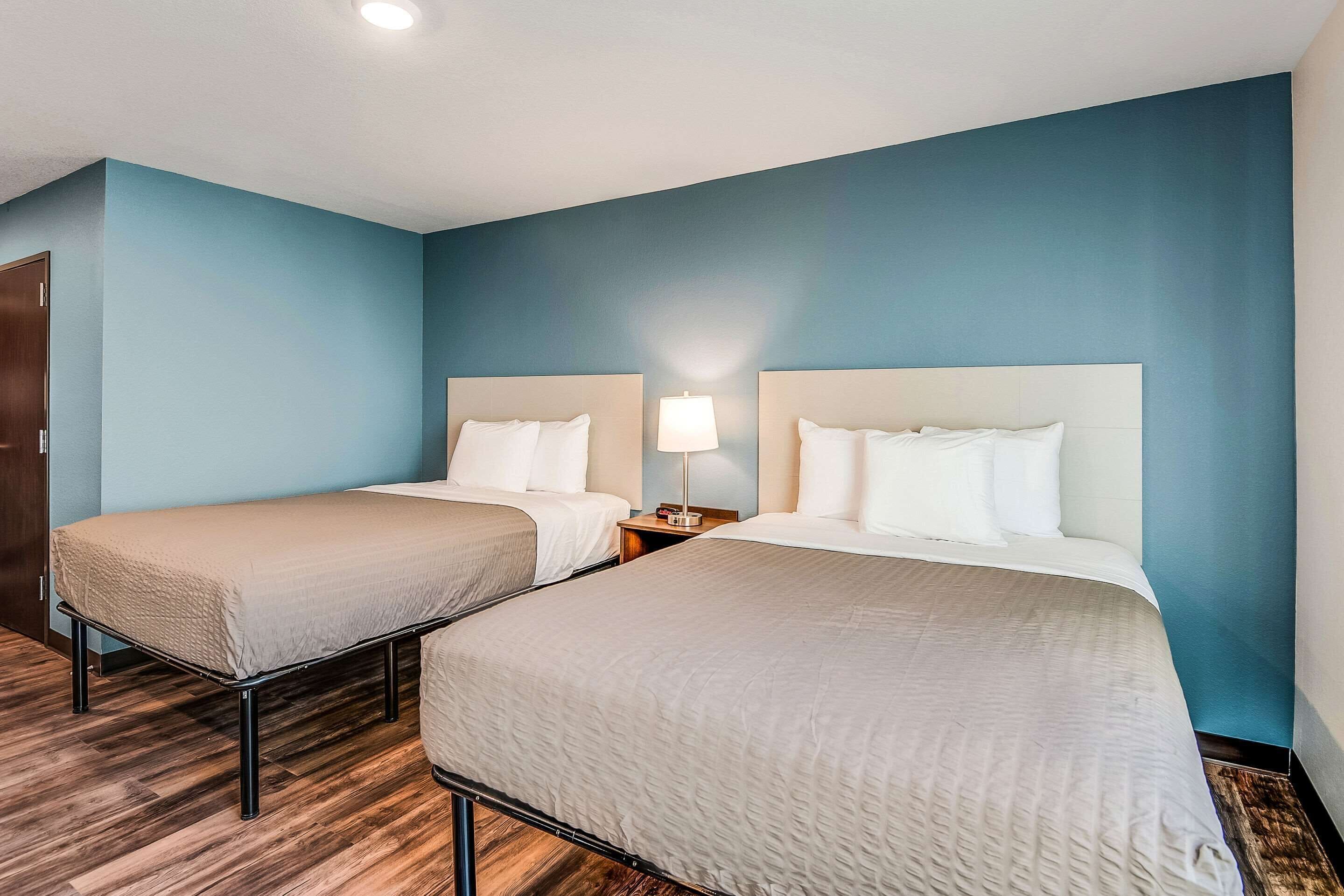Une chambre d’hôtel avec deux lits, une table de chevet avec une lampe et un plancher en bois.