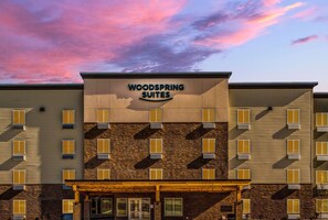 A hotel with a sign reading "WOODSPRING SUITES" and a brick facade. - Woodspring Suites  West Des Moines (West Des Moines)