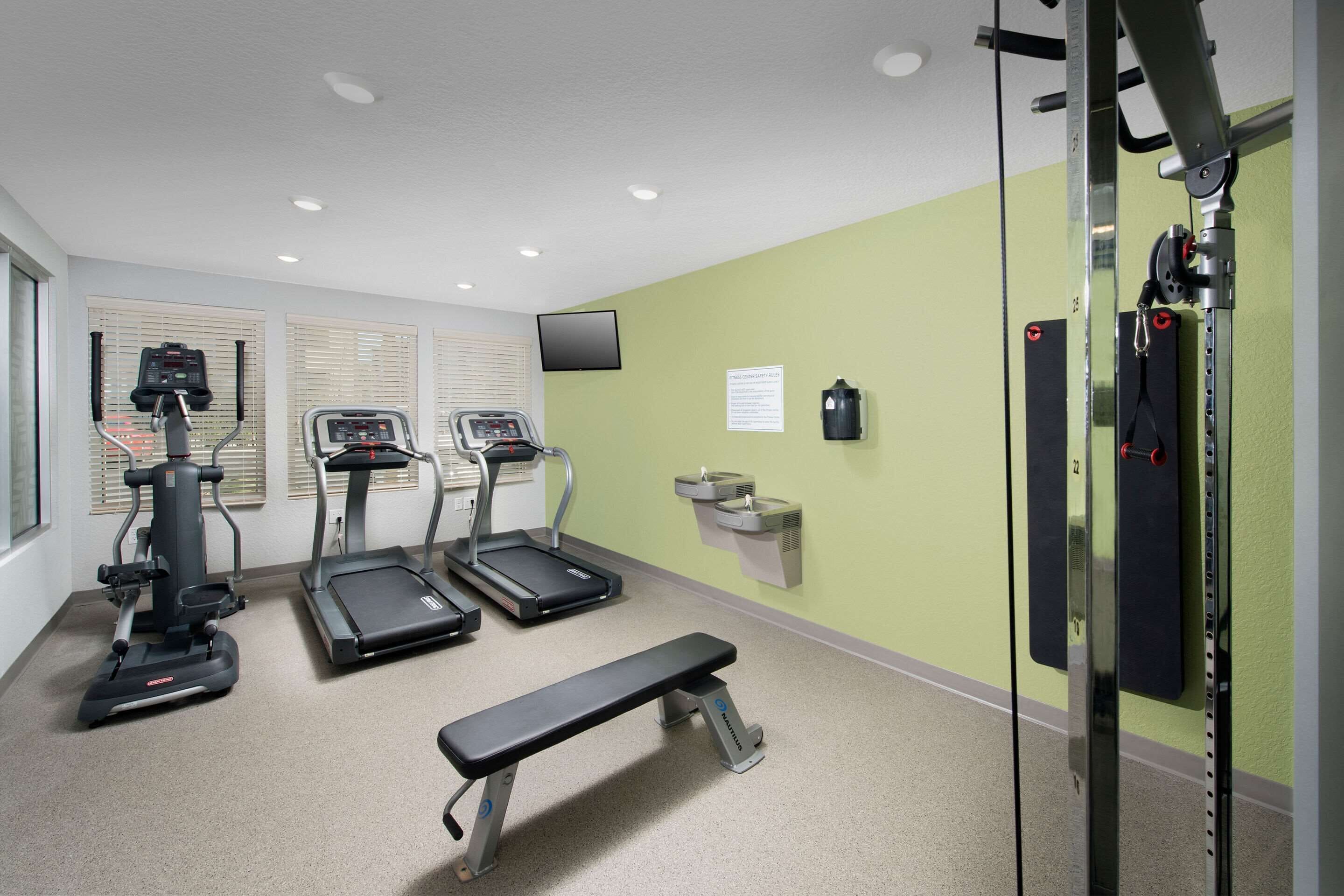 Una palestra con tapis roulant, una panca e attrezzature per sollevamento pesi.
