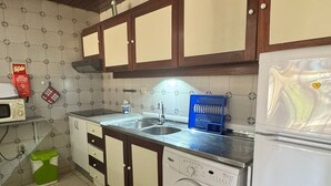 A compact kitchen with a washing machine, a sink, and a refrigerator. - Nautilus A (Quarteira)