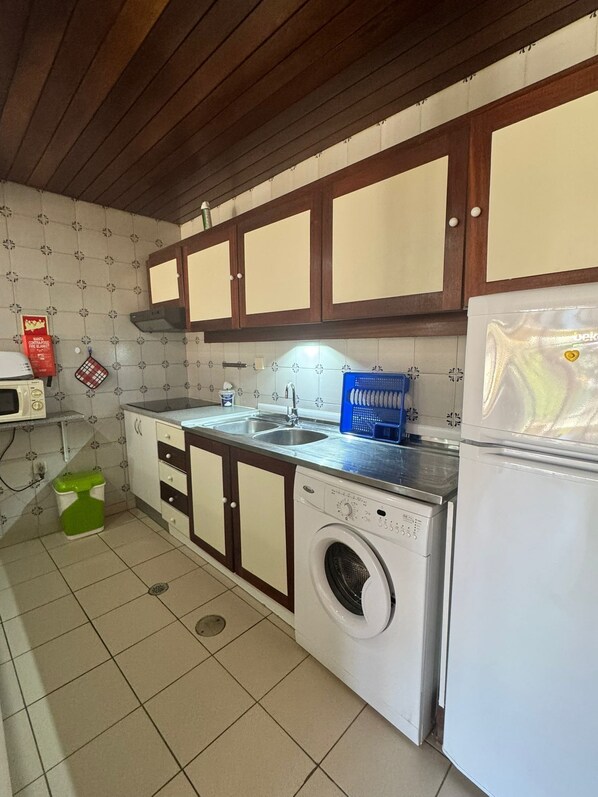 Una cocina compacta con lavadora, lavaplatos y refrigerador.