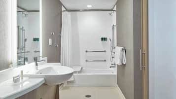 A modern bathroom with a sink, mirror, shower, and bathtub.