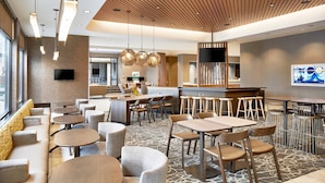 A modern hotel lobby with round tables, sofas, and a bar area.