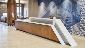 A modern reception area with a wooden reception desk, a large wall with geometric patterns, and a seating area with sofas and a coffee table.