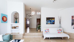 Un salon moderne avec un canapé, une table basse et des objets décoratifs. Un escalier mène à une autre pièce.