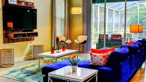 A living room with a TV, two chairs, a sofa, a table, and a large window. - Secret Cove (Davenport)