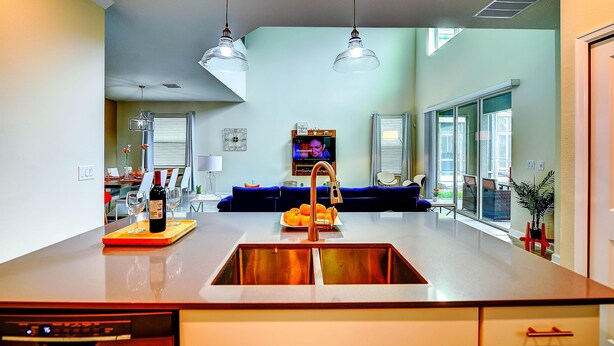 A modern kitchen with a central island, double sink, and pendant lighting. - Secret Cove (Davenport)