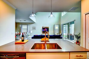 A modern kitchen with a central island, double sink, and pendant lighting. - Secret Cove (Davenport)
