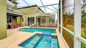 A pool area with a glass enclosure, a lounge area with seating, and a view of the outdoors. - Secret Cove (Davenport)