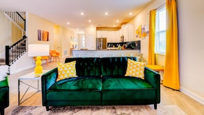 Un salon moderne avec un canapé vert, des coussins jaunes et une table basse blanche.