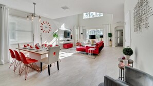 A spacious living area with a dining table, red chairs, a red sofa, and a TV. - Ruby Falls Villa (Kissimmee)