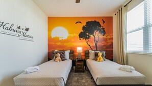 A hotel room with two beds, a sunset mural, a small table with a lamp, and a window with curtains. - Ruby Falls Villa (Kissimmee)