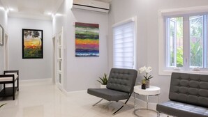 Ein modernes Wohnzimmer mit einem grauen Sofa, einem kleinen runden Tisch mit Pflanze und einem farbenfrohen, abstrakten Gemälde an der Wand.
