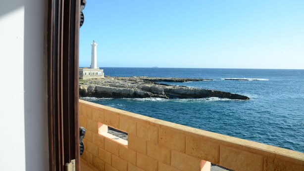 A balcony with a view of the sea, a lighthouse, and rocky coastline. - Apartment by the sea (Augusta)