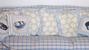A bedroom with a large wave painting on the wall, a chandelier, and a bed with checkered bedding. - Apartment by the sea (Augusta)